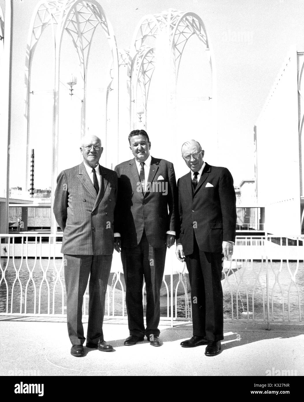 A piena lunghezza Ritratto di gruppo di American Educational Amministratore e Presidente della Johns Hopkins University Milton Stover Eisenhower (a destra), il fratello Edgar Dadosul Eisenhower (sinistra) e Seattle avvocato e leader civico Joseph Gandy Edward (centro) in piedi davanti ad una fontana e archi presso il Seattle Fiera Mondiale del 1962. Foto Stock