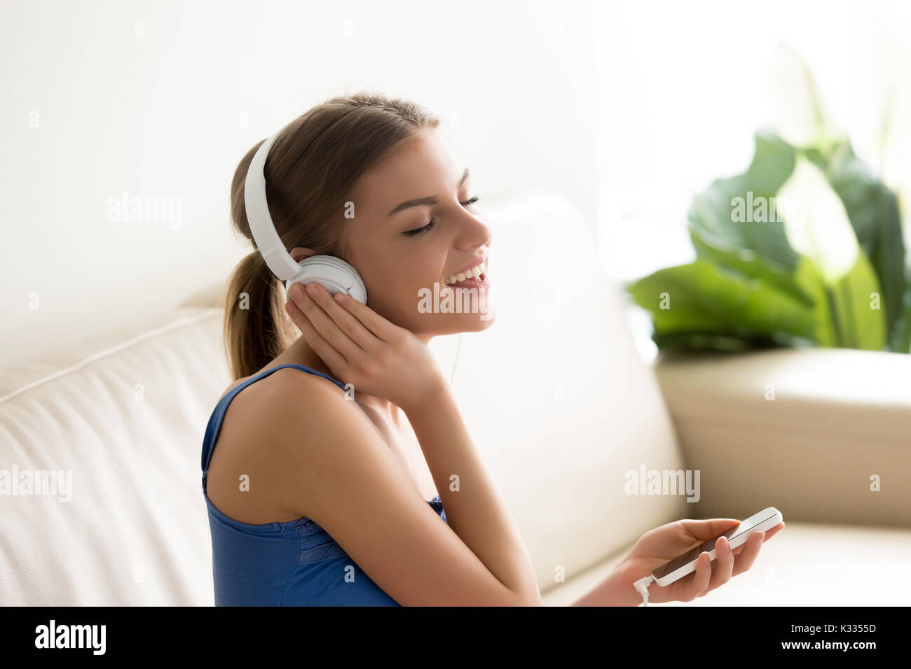 Ritratto di bella giovane donna in cuffia seduti sul divano e Foto Stock
