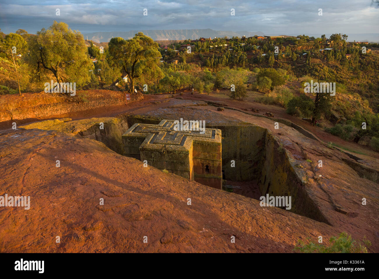 Golden Sunset luce proveniente sotto nubi e afferrando la parte superiore dell'antico in pietra scolpiti Giyorgis Bet (Chiesa di San Giorgio), Lalibela, Etiopia Foto Stock