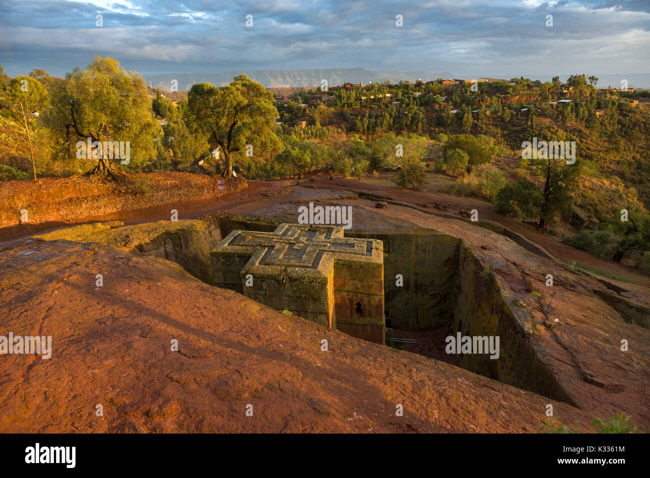 Golden Sunset luce proveniente sotto nubi e afferrando la parte superiore dell'antico in pietra scolpiti Giyorgis Bet (Chiesa di San Giorgio), Lalibela, Etiopia Foto Stock