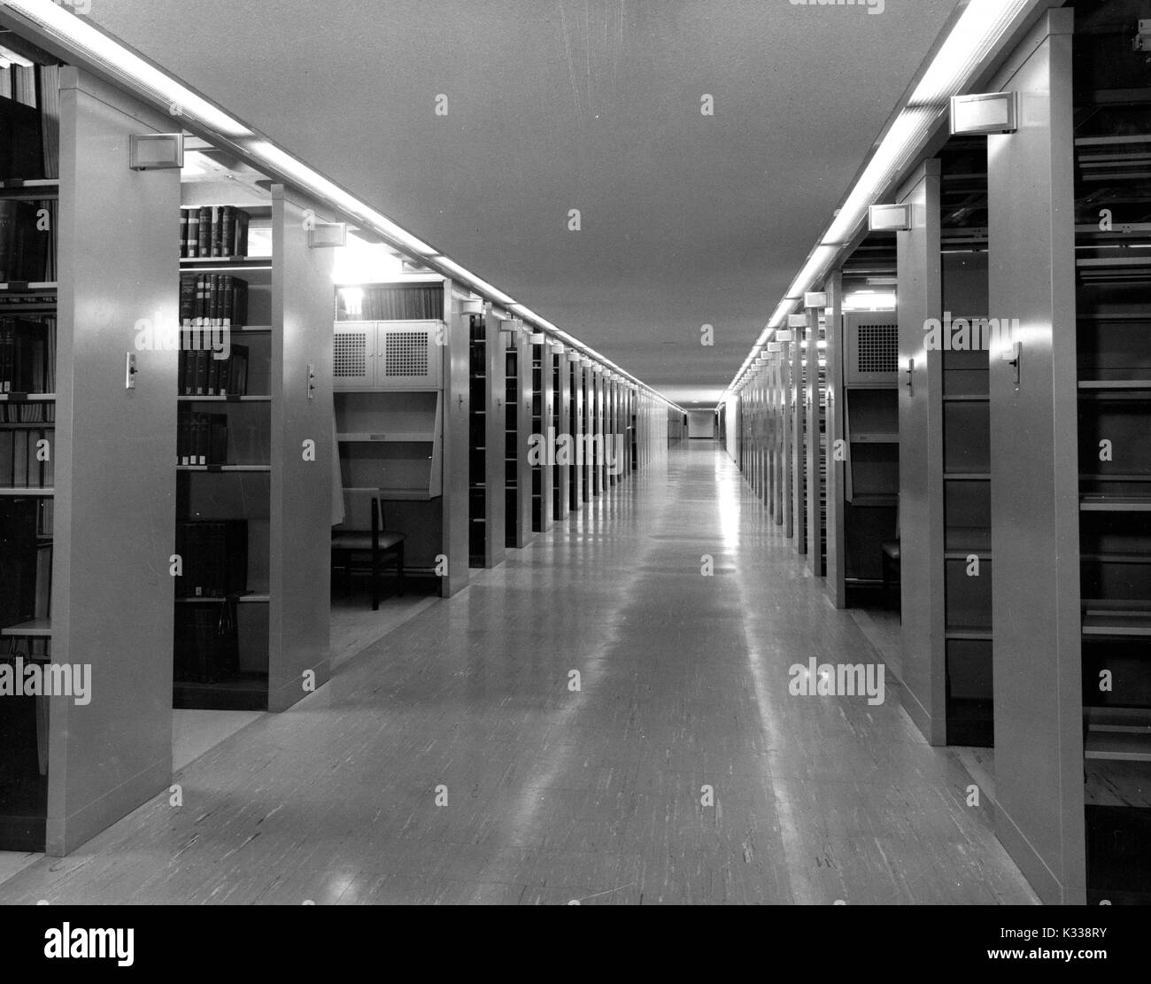 Un lungo corridoio vacante con pile di libri su un livello sotterraneo dentro il Milton S Eisenhower biblioteca presso la Johns Hopkins University, Baltimora, Maryland, 1975. Foto Stock