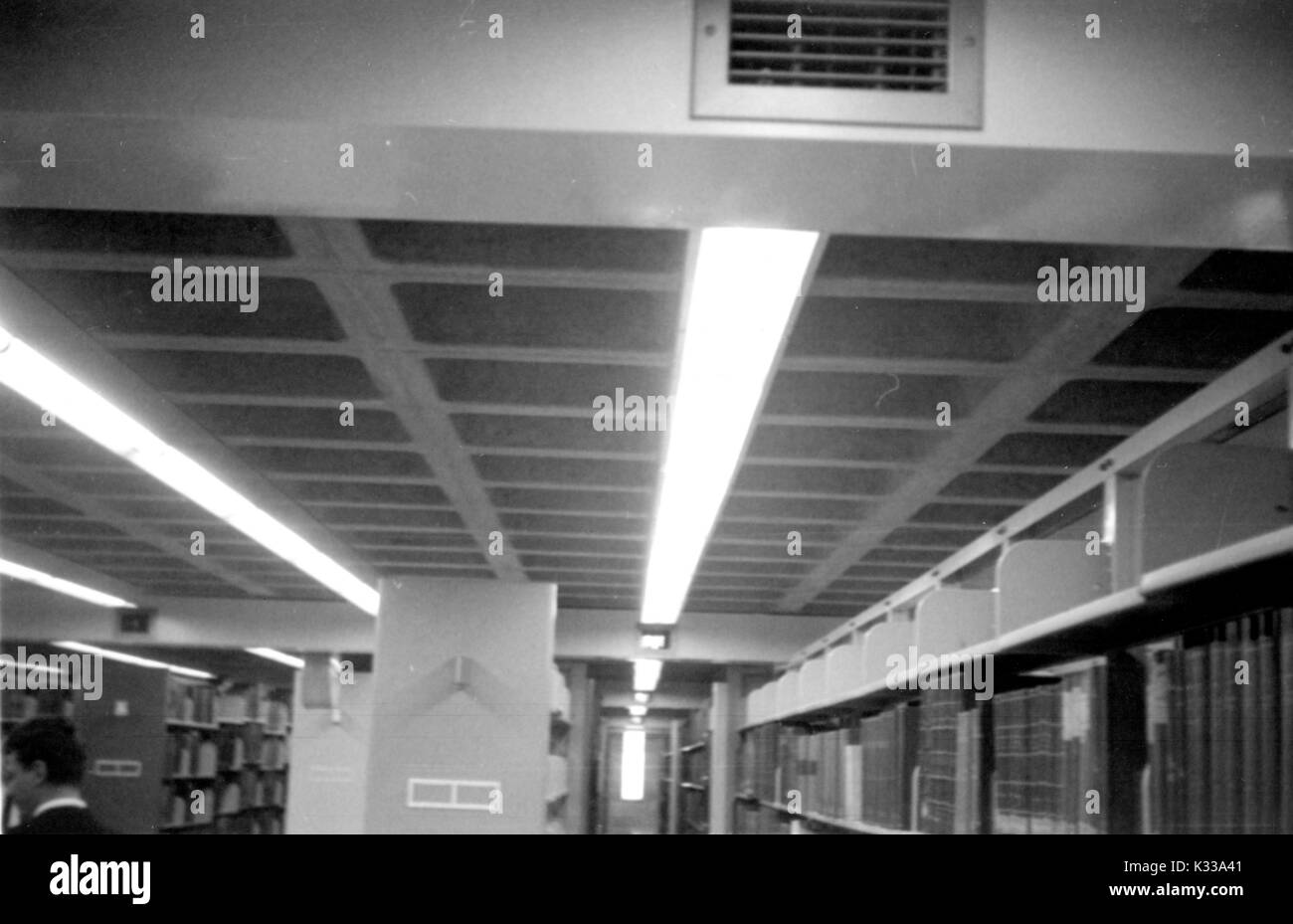 All'interno di un livello dello stack di Milton S Eisenhower biblioteca presso la Johns Hopkins University, righe di libri di stand da pavimento a soffitto, con lunghi fasci di luce che illuminano le pile, Baltimore, Maryland, 1930. Foto Stock