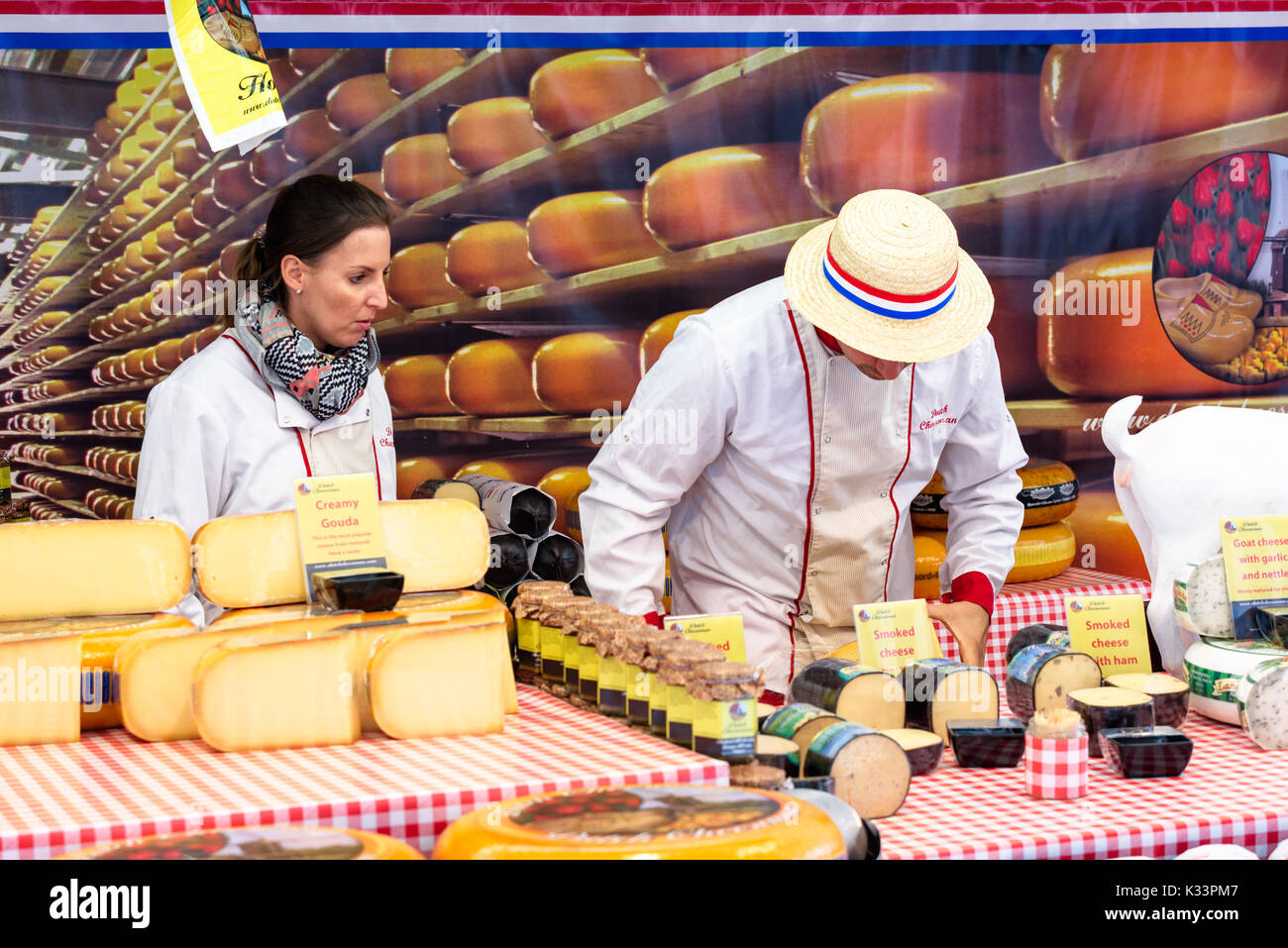 Kristiansand, Norvegia - 16 agosto 2017: Travel documentario di strada del mercato. I fornitori di formaggio circa per sollevare un pezzo di formaggio affumicato dall'assortimento Foto Stock