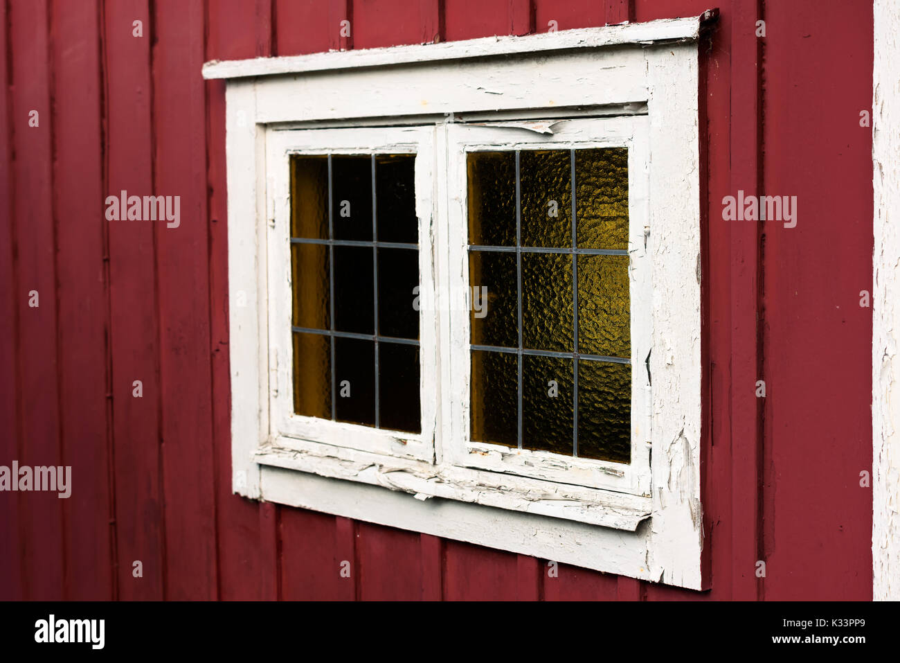 Vecchia finestra su un cottage di rosso con il bianco sul telaio di una finestra. La cornice bianca è lo sfaldamento e nel bisogno di attenzione. Portare i sottili montanti o barre di smaltatura sul vetro w Foto Stock