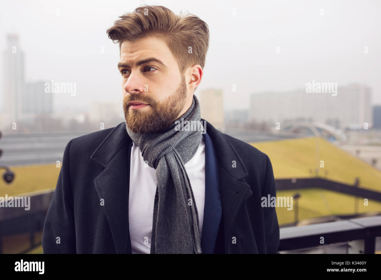Una foto di giovani, uomo bello che indossa un cappotto e uno scialle. Egli  sta cercando da parte Foto stock - Alamy