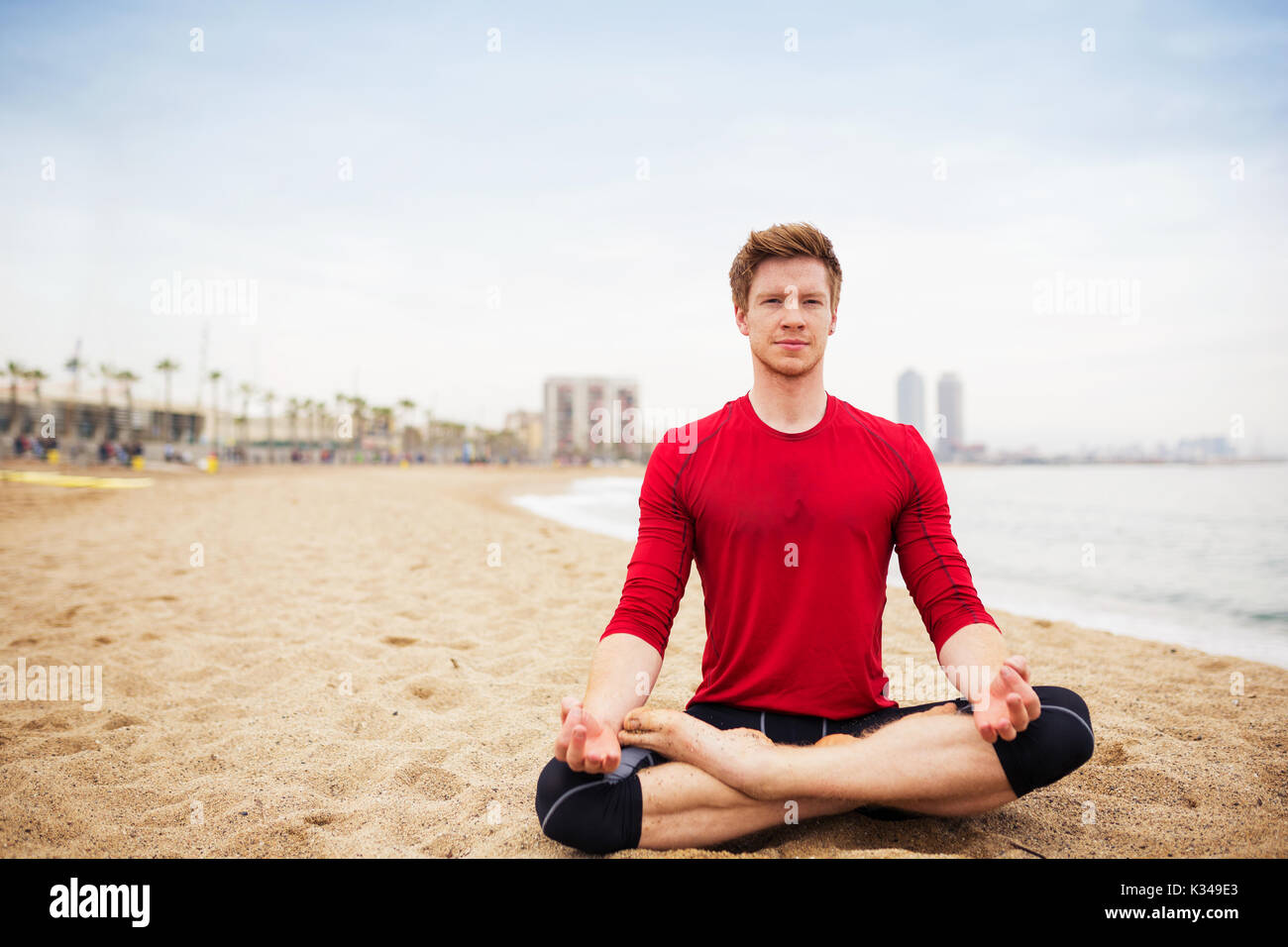 Una foto del giovane e sportivo da uomo seduto sulla spiaggia e la meditazione. Foto Stock