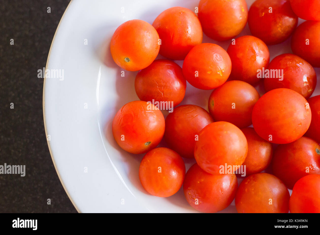 Mazzetto di deliziosi pomodori ciliegia in una piastra bianca. Foto Stock