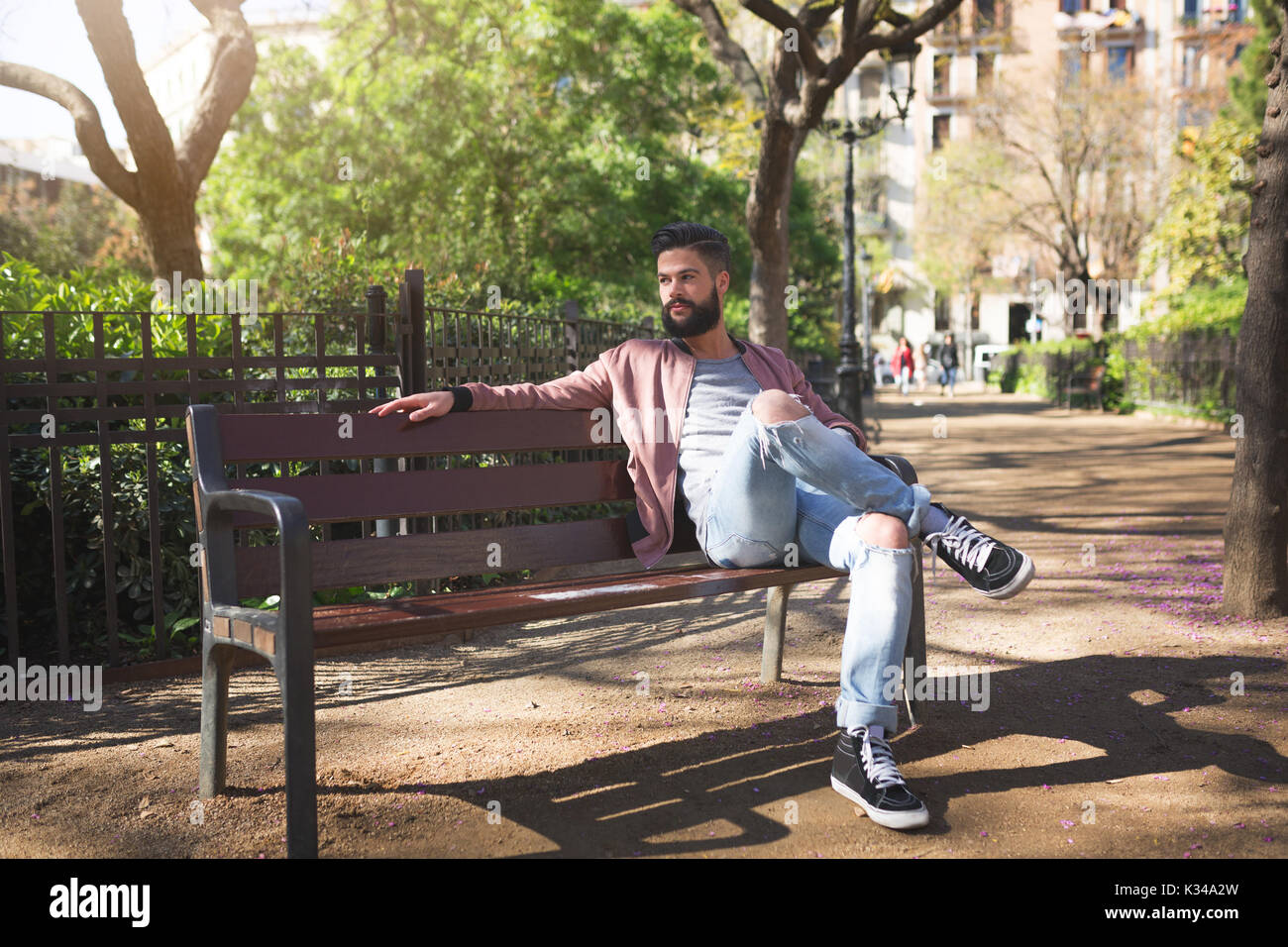 La foto di un giovane uomo seduto sulla panchina del parco e godendo il suo tempo libero. Foto Stock