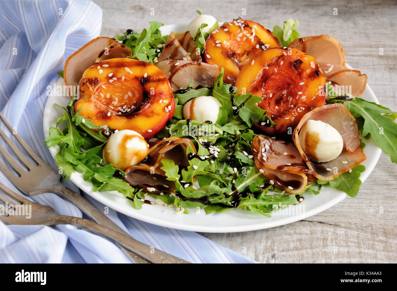 Insalata con prosciutto e grigliate di pesche noci, mozzarella e foglie di rucola Foto Stock