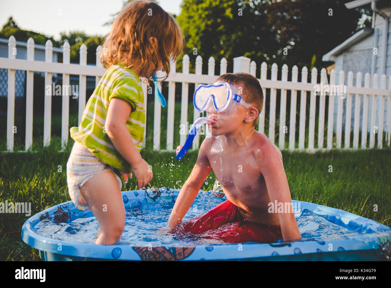 Un ragazzo che indossa un scuba mask guarda una bambina in una piscina per bambini Foto Stock