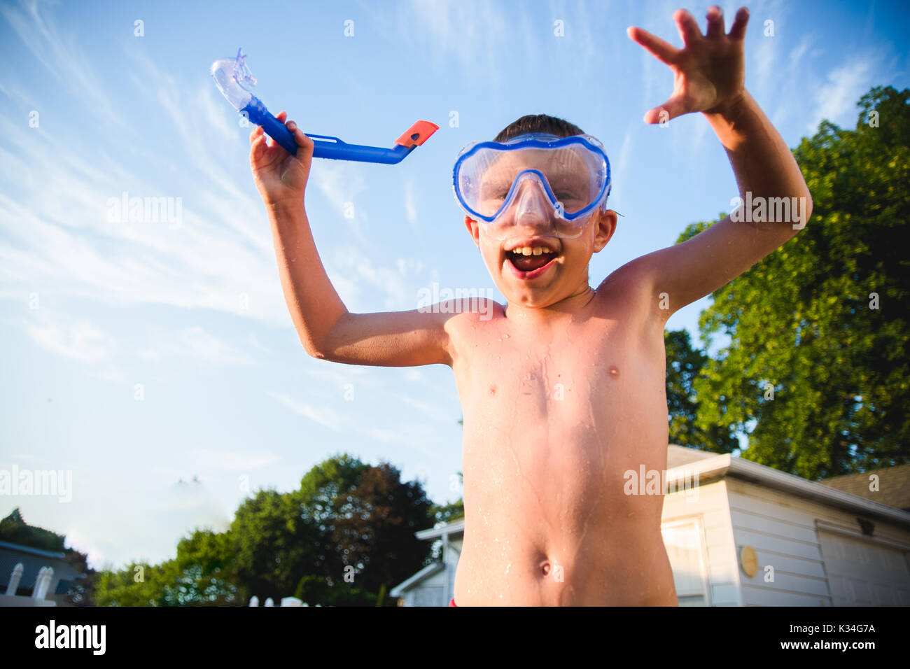 Un ragazzo indossa una maschera scuba contro un cielo azzurro con poche nuvole. Foto Stock