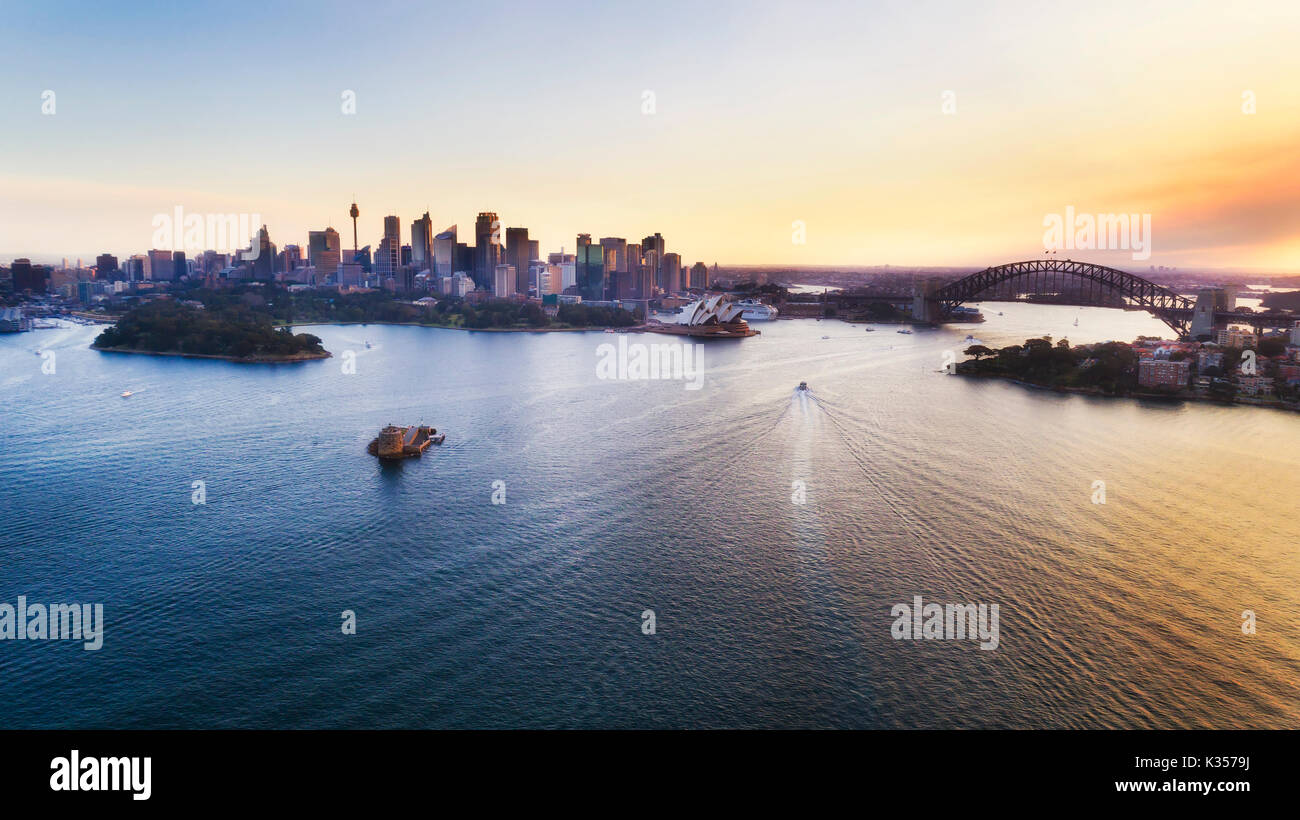 Colorato tramonto sulla città di Sydney CBD e punti di riferimento porto ad elevati vista aerea sopra le acque del porto. Foto Stock