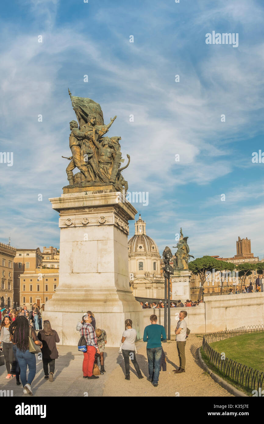 I turisti a piazza Venezia nella parte anteriore della scultura in bronzo all'entrata al monumento nazionale a Vittorio Emanuele II Foto Stock