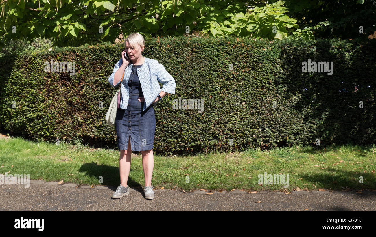 Una donna a parlare su un telefono mobile nel parco Foto Stock