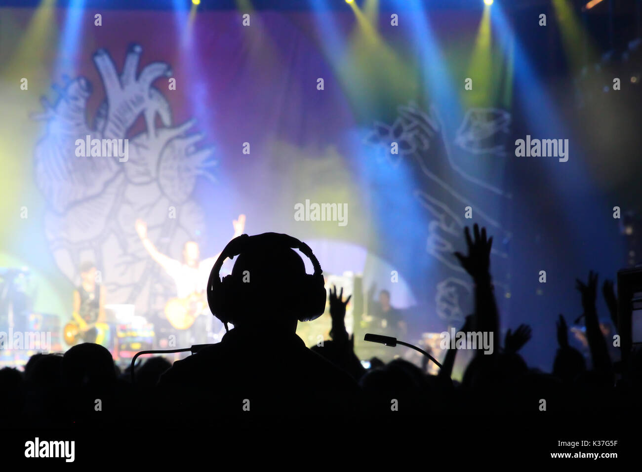 Stadio di concerto con silhouette di tecnico del suono in cuffia e le mani alzate del pubblico Foto Stock
