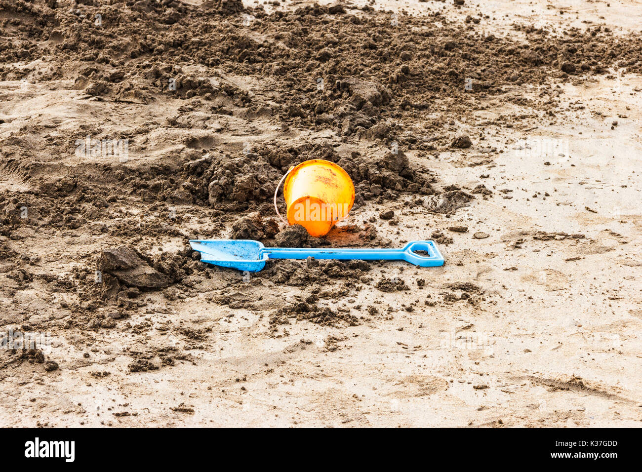 Blu e arancione secchio di plastica e vanga giacenti abbandonati sulla spiaggia sabbiosa a Westward Ho, Devon, Regno Unito Foto Stock