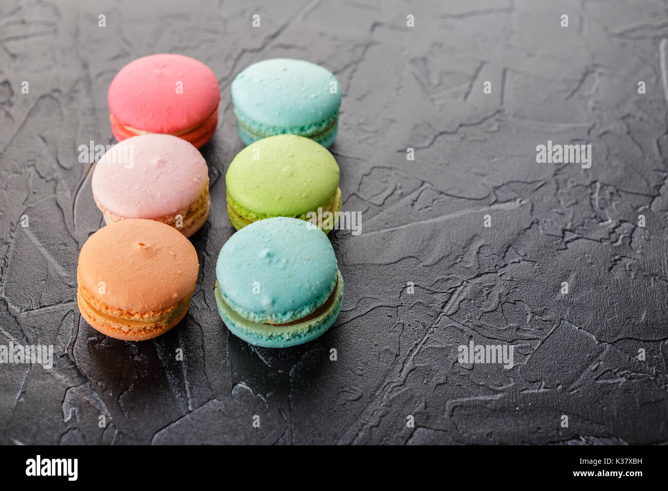 Classica francese amaretto multicolore biscotti nero su sfondo di calcestruzzo Foto Stock