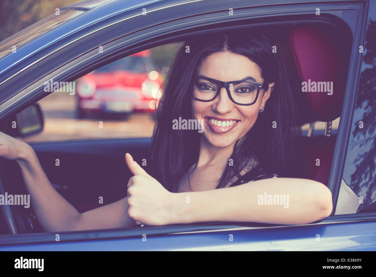 Felice donna seduta dentro la sua nuova vettura che mostra pollice in alto Foto Stock