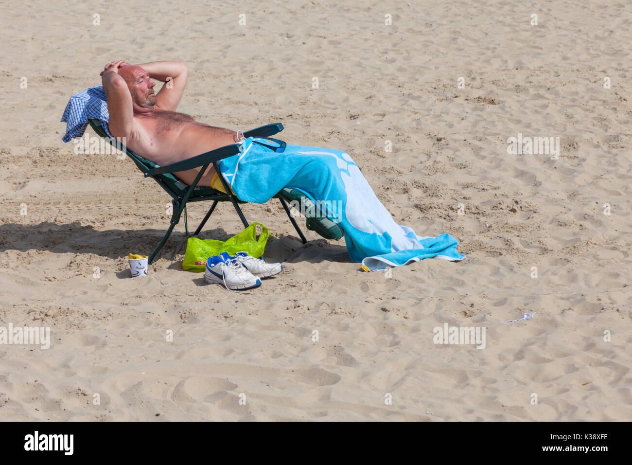 Uomo di mezza età a prendere il sole sulla spiaggia UK Gran Bretagna Foto Stock