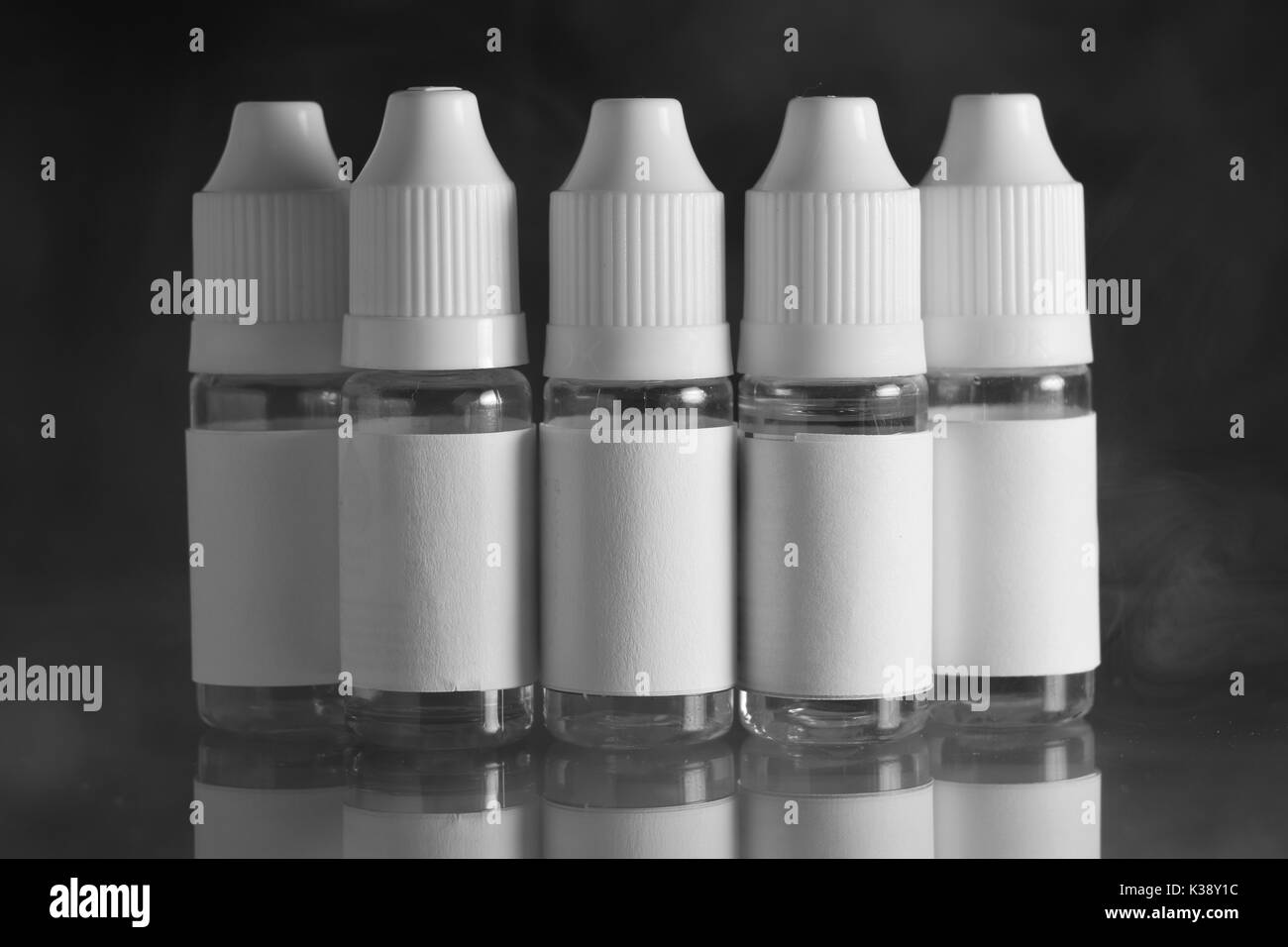 Isolato e bottiglie di liquido per dispositivi vaping, e sigaretta, sigaretta elettronica, su uno sfondo nero. Foto Stock