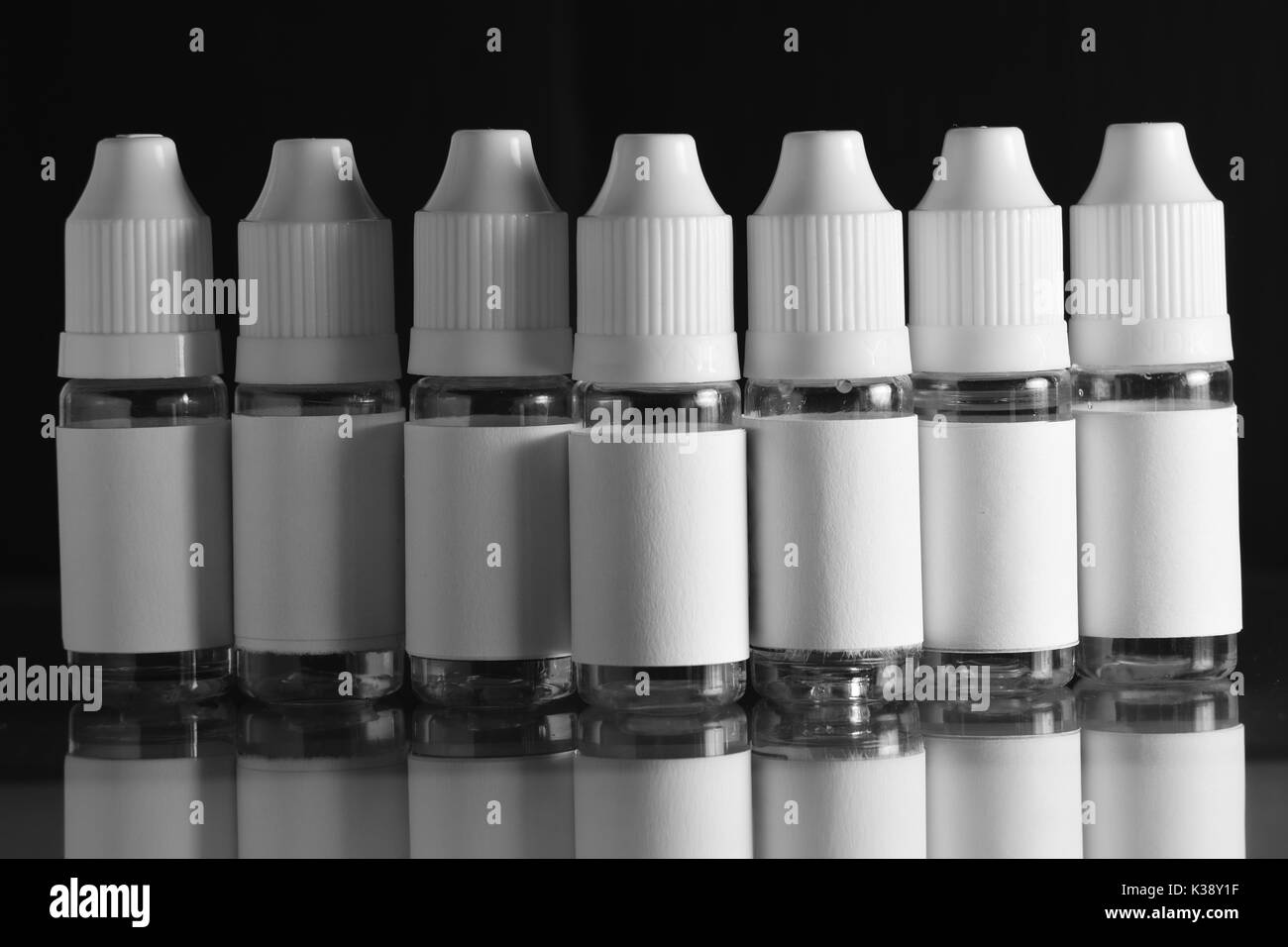 Isolato e bottiglie di liquido per dispositivi vaping, e sigaretta, sigaretta elettronica, su uno sfondo nero. Foto Stock