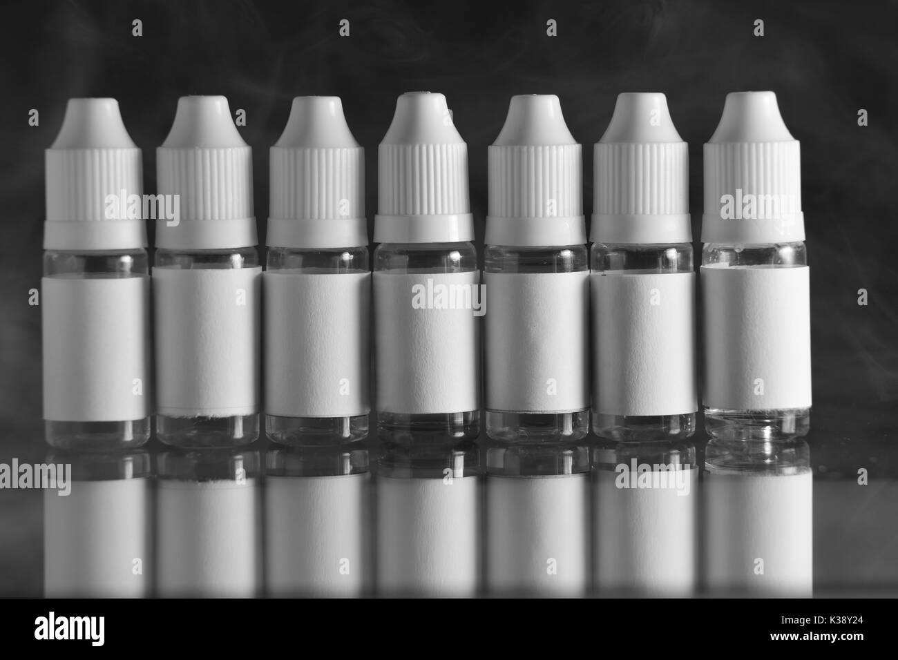 Isolato e bottiglie di liquido per dispositivi vaping, e sigaretta, sigaretta elettronica, su uno sfondo nero. Foto Stock
