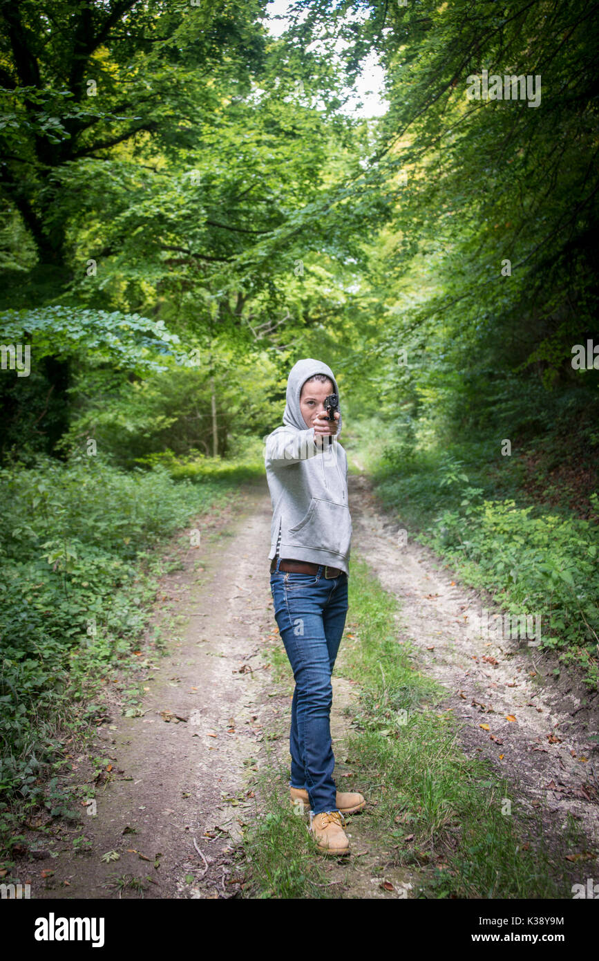 Donna indicando una pistola di indossare una felpa con cappuccio Foto Stock