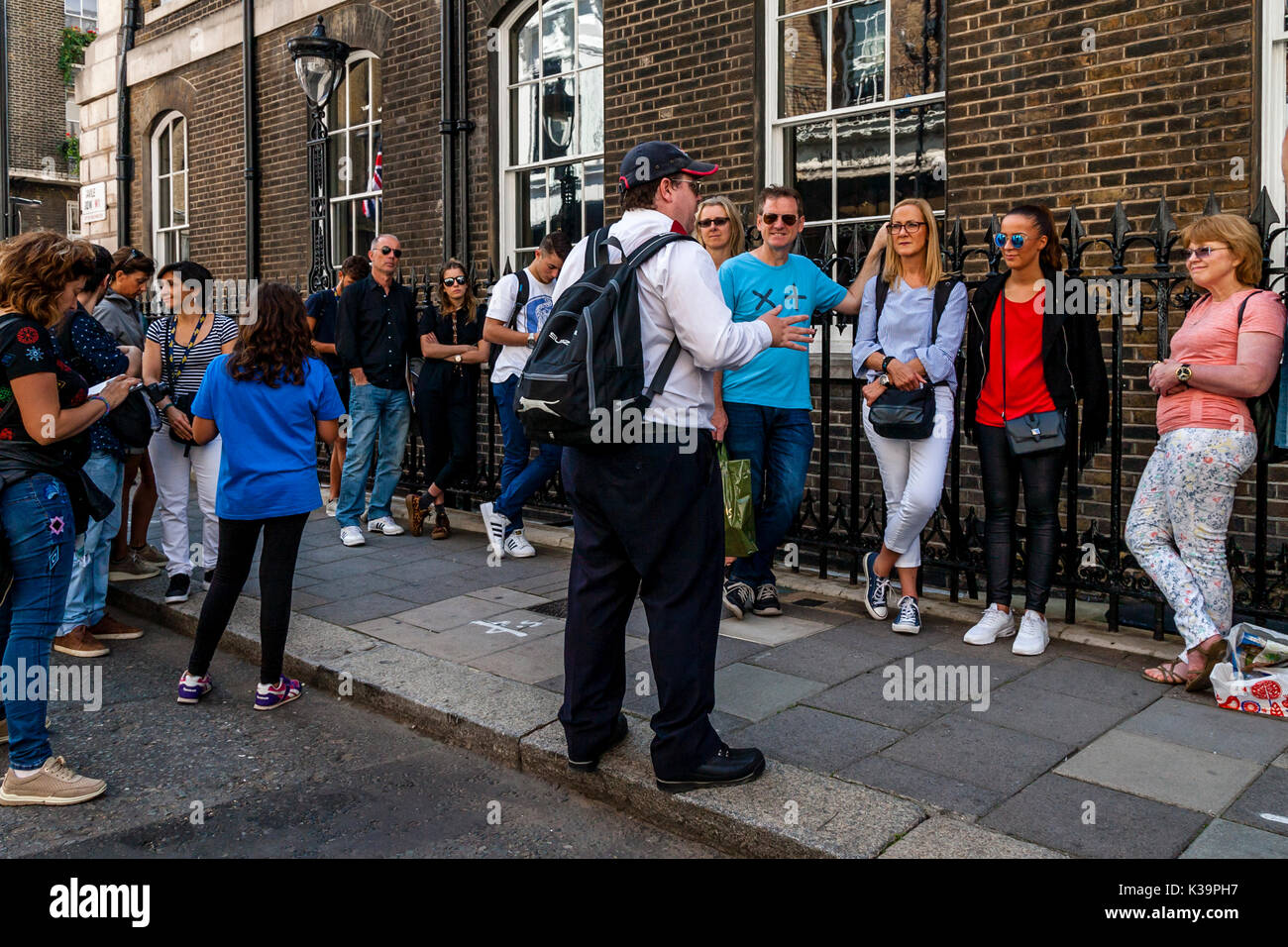 I turisti in ascolto per un tour di Londra guida, Mayfair, London, Regno Unito Foto Stock