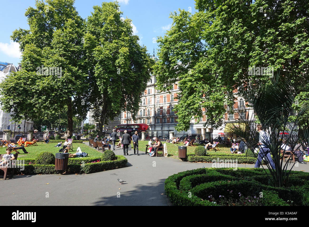 Una vista di persone relax su una soleggiata giornata estiva in Grosvenor Gardens a Londra REGNO UNITO Foto Stock