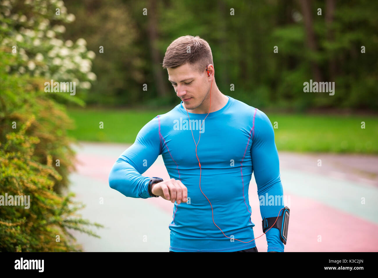 Una foto di giovani, ben costruito uomo controllando il suo tempo di esecuzione. Foto Stock