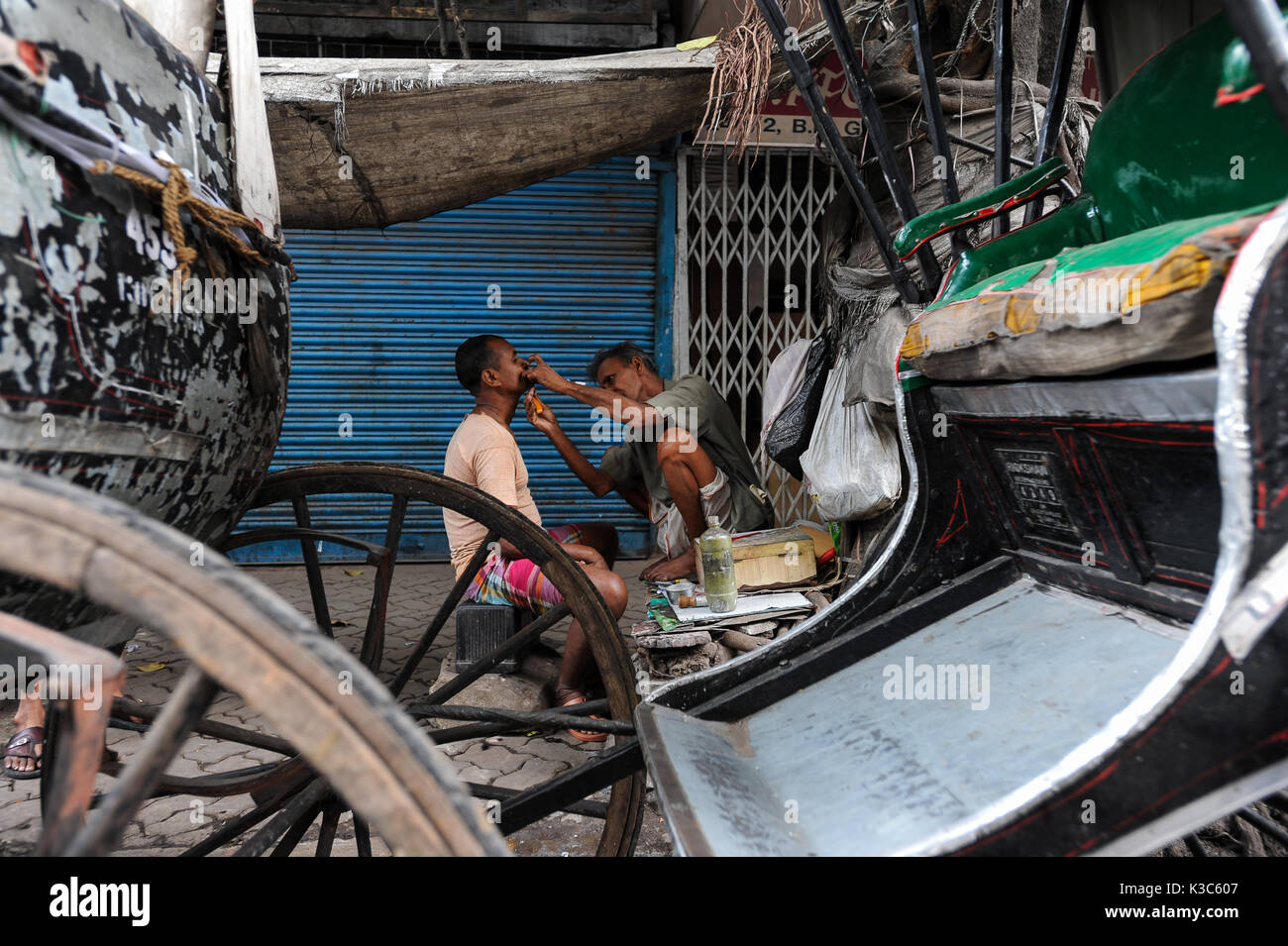 20.02.2011, Calcutta, West Bengal, India, Asia - un uomo viene rasato tra rickshaws in corrispondenza di un bordo strada in Kolkata. Foto Stock