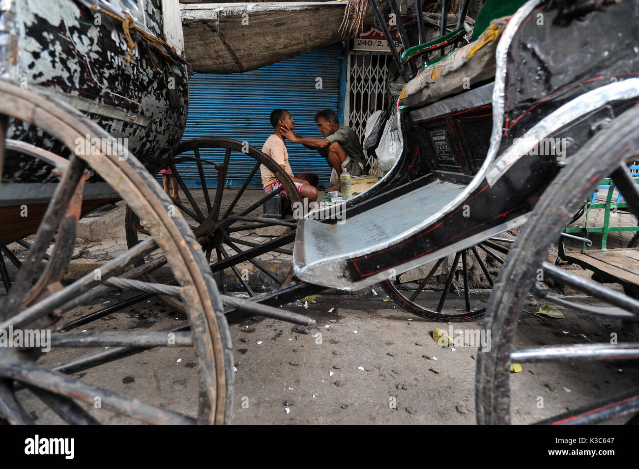 20.02.2011, Calcutta, West Bengal, India, Asia - un uomo viene rasato tra rickshaws in corrispondenza di un bordo strada in Kolkata. Foto Stock