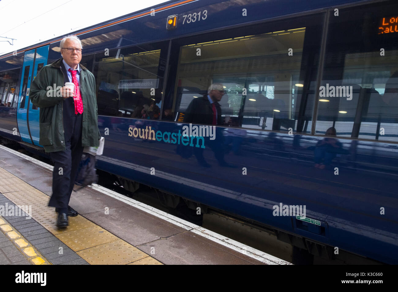 Business " commuter " cammina accanto a un treno di sud-est di stanza a Ashford International station, Kent Foto Stock