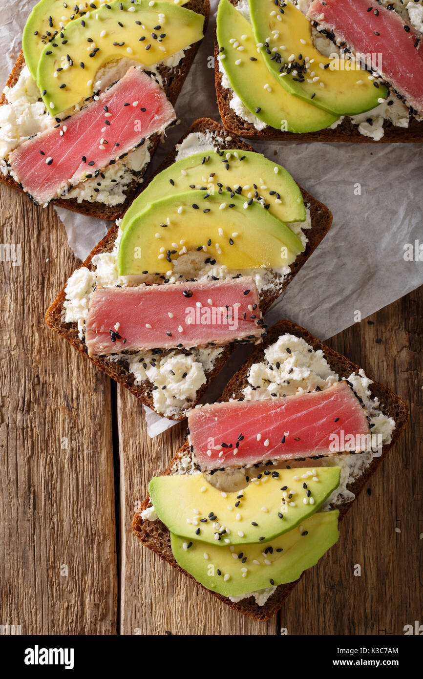 Panini con filetto di tonno, avocado e crema di formaggio vicino sul tavolo. Vista dall'alto in verticale Foto Stock Panini con filetto di tonno, avocado e crema di formaggio vicino sul tavolo. Vista dall'alto in verticale Foto Stock
