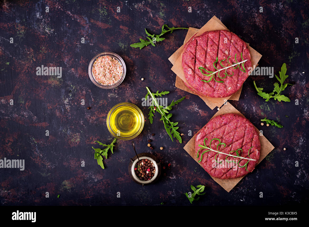 Crudo fresco in casa le carni bovine macinate hamburger di manzo con spezie su sfondo nero Foto Stock