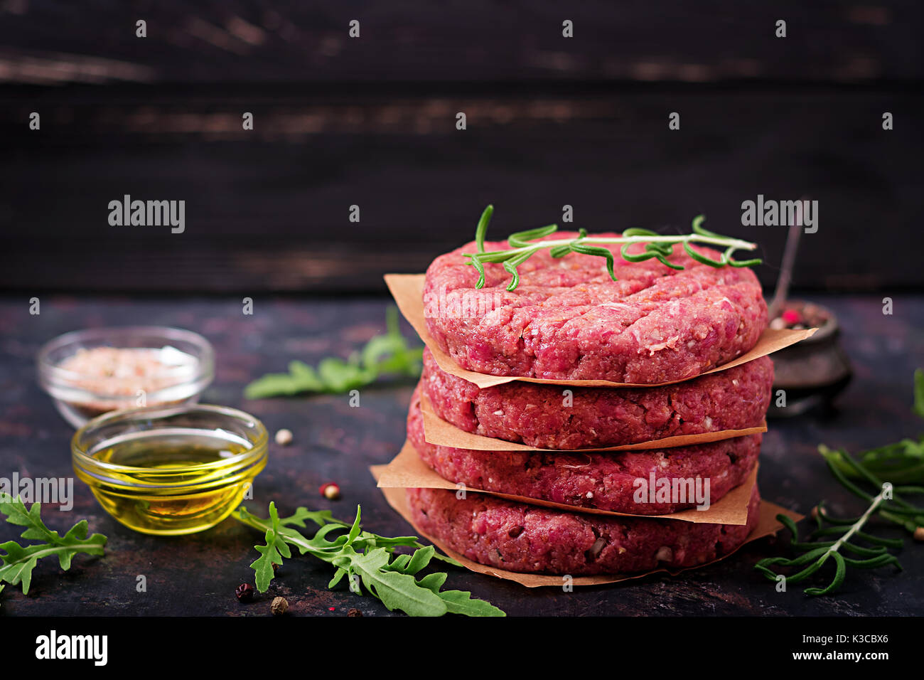 Crudo fresco in casa le carni bovine macinate hamburger di manzo con spezie su sfondo nero Foto Stock