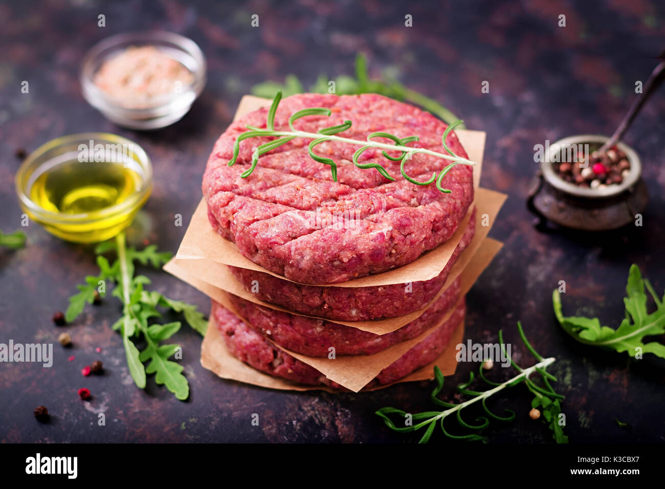 Crudo fresco in casa le carni bovine macinate hamburger di manzo con spezie su sfondo nero Foto Stock