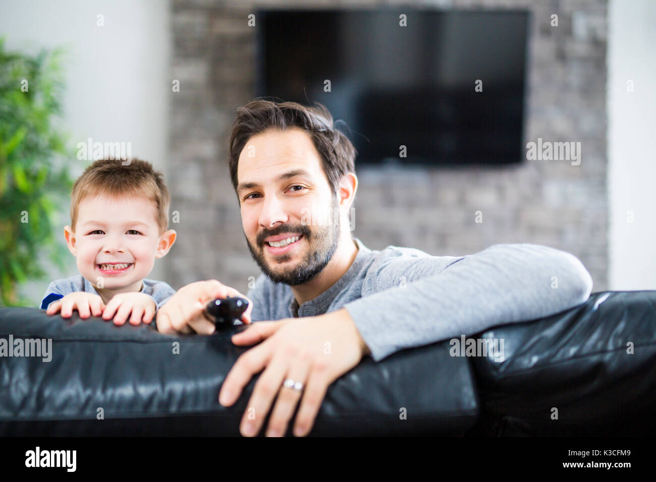 Padre e figli sul divano a casa a guardare la TV insieme Foto Stock