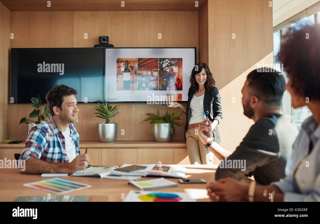 Collega femmina rendendo le presentazioni durante le riunioni aziendali in ufficio. Gruppo di progettisti creativi discutendo nuove idee di marketing insieme in boardroo Foto Stock