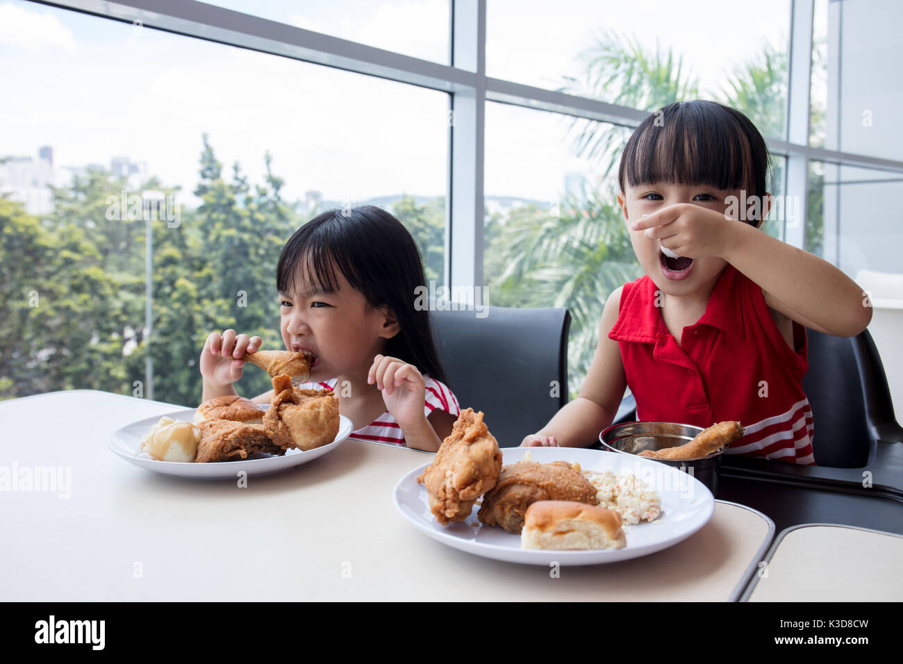 Cinese asiatici bambine di mangiare pollo fritto al ristorante al coperto Foto Stock