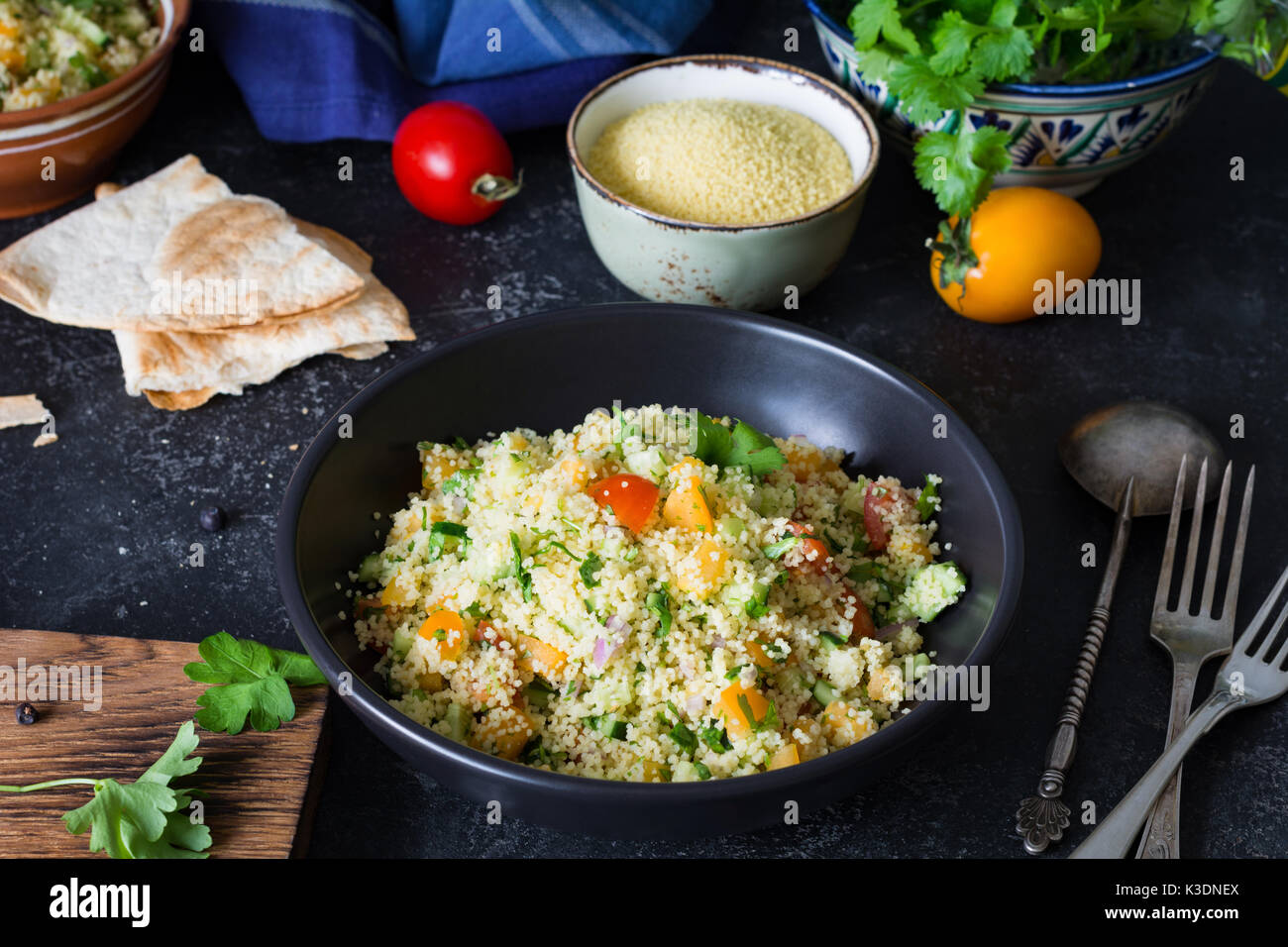 Arabo libanese cucina: una sana deliziosa insalata di cous cous, verdure fresche e verdi chiamato tabulé in nero ciotola. autentica cucina Foto Stock