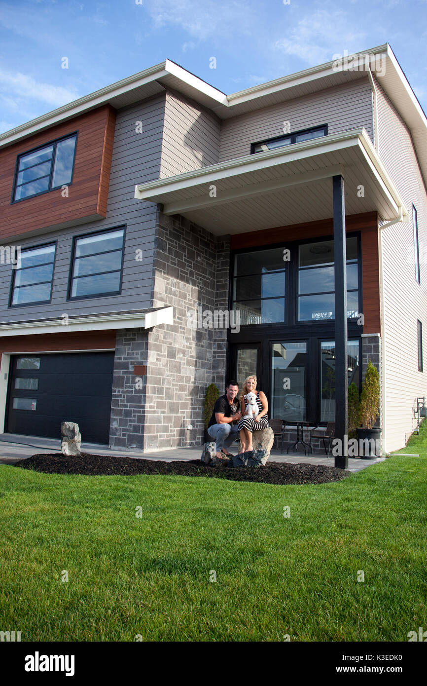 Bella giovane sedersi fuori il loro modello casa da sogno Foto Stock