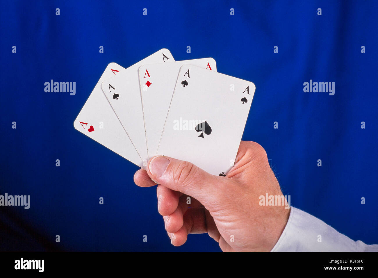 Mano trattiene ventaglio giocando a carte con quattro assi Foto Stock