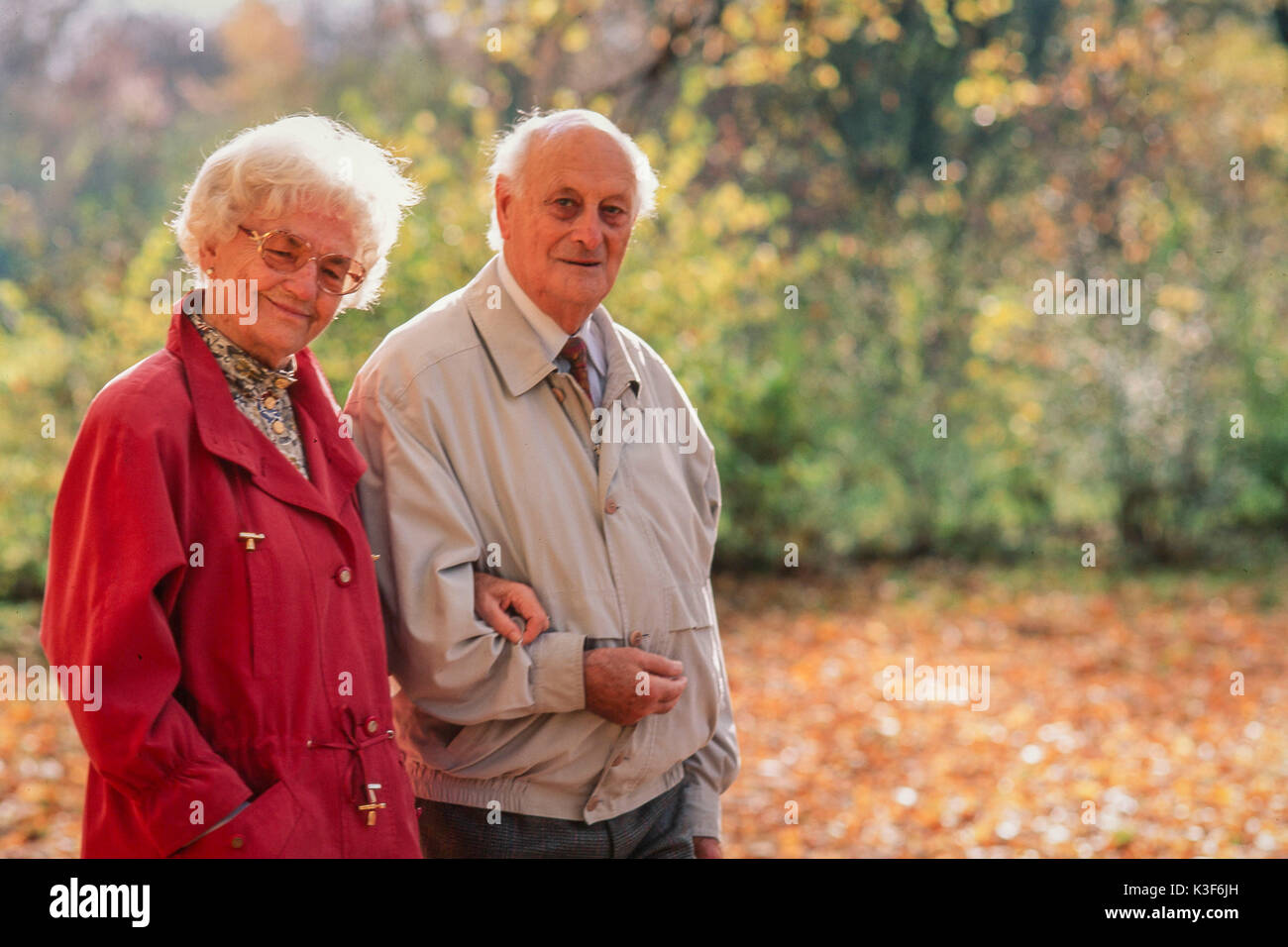 Senior Citizen's giovane passa per una passeggiata a braccetto in legno Foto Stock