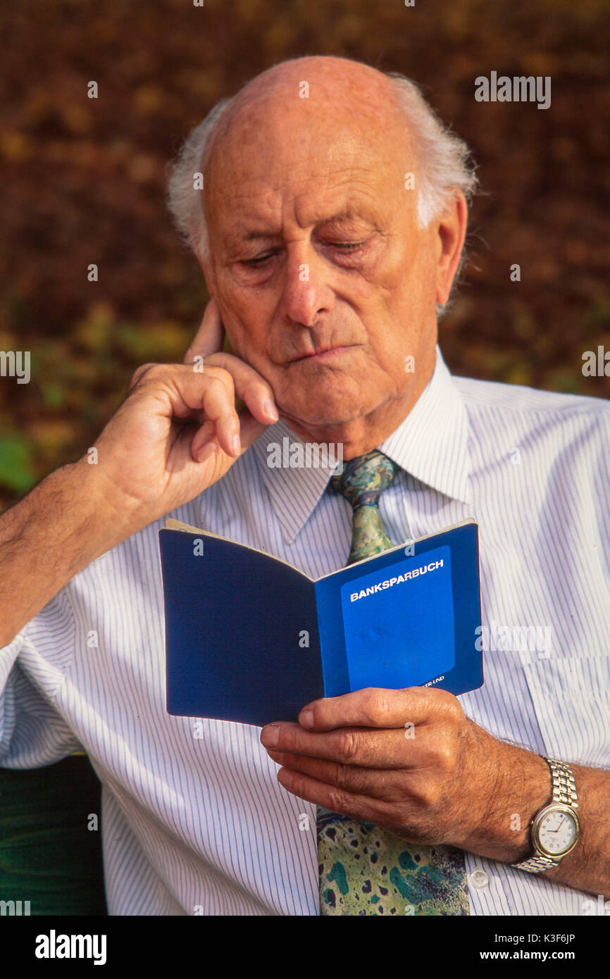 Senior guarda nel suo bankbook Foto Stock