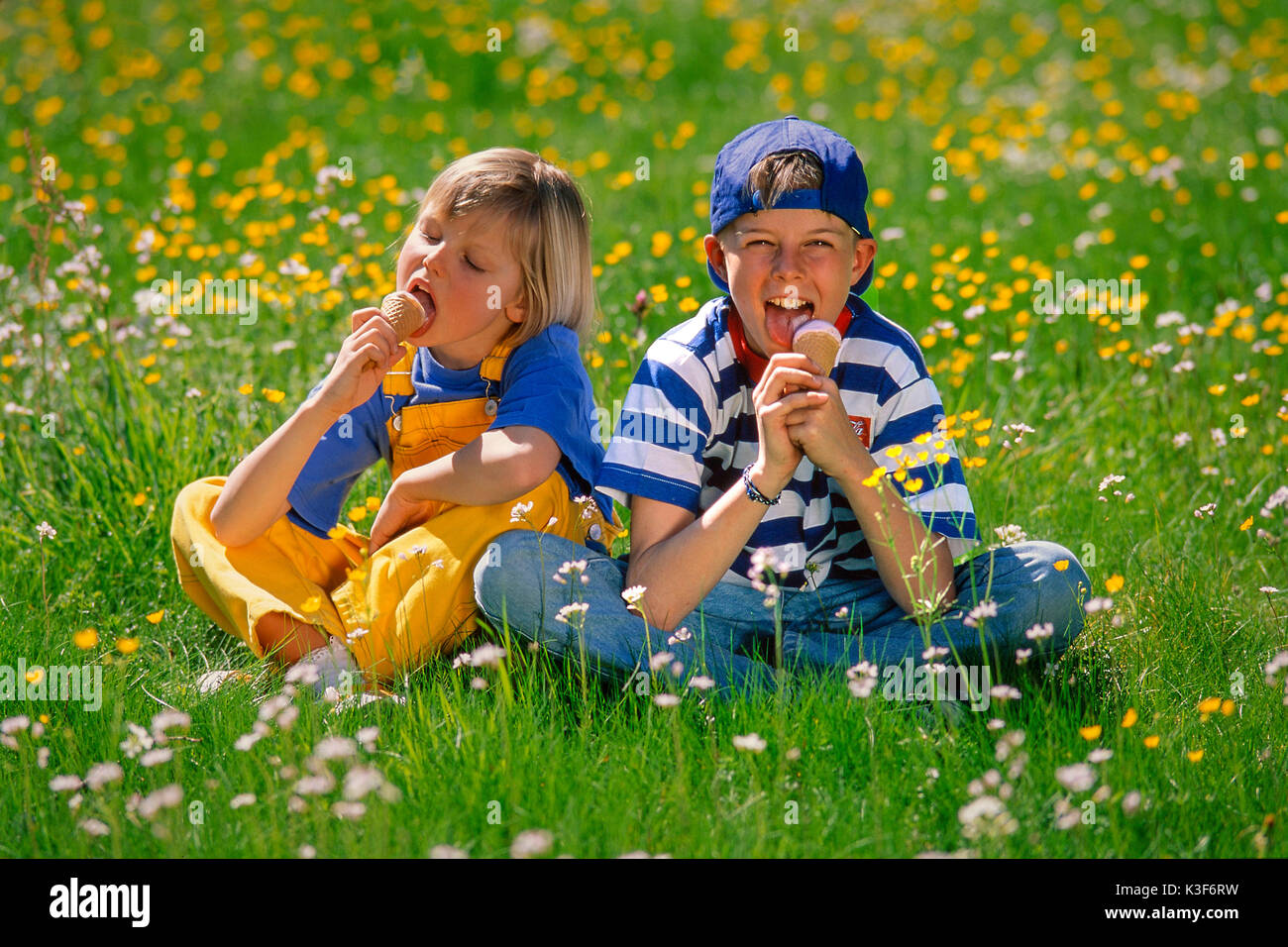 I bambini mangiano il ghiaccio nel prato di primavera Foto Stock