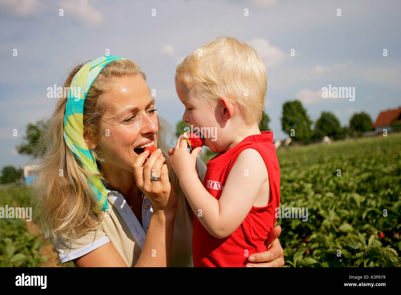 Madre e figlio mangiare fragole Foto Stock