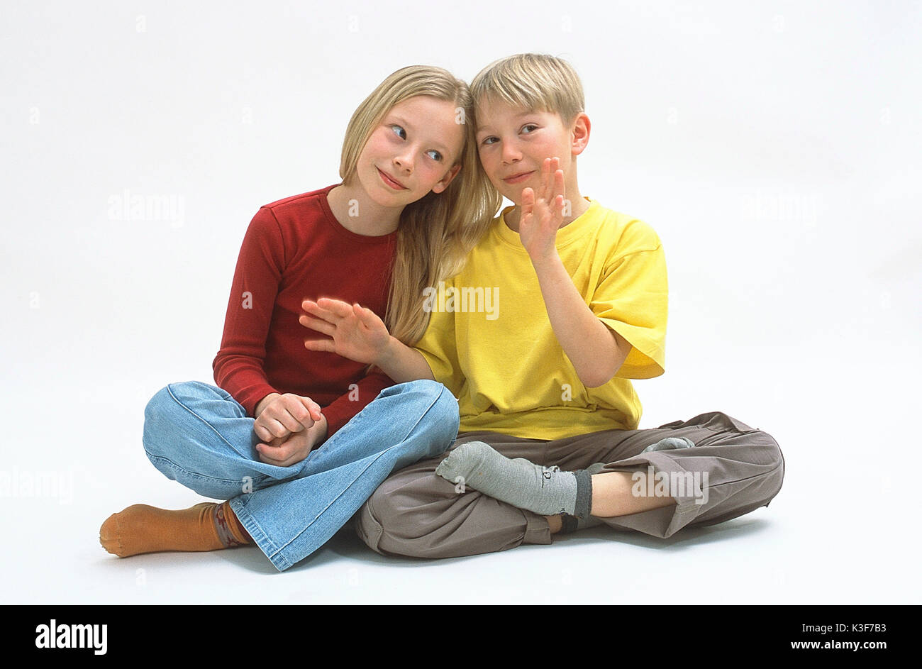 Ragazzo e una ragazza sedersi a gambe incrociate Foto Stock