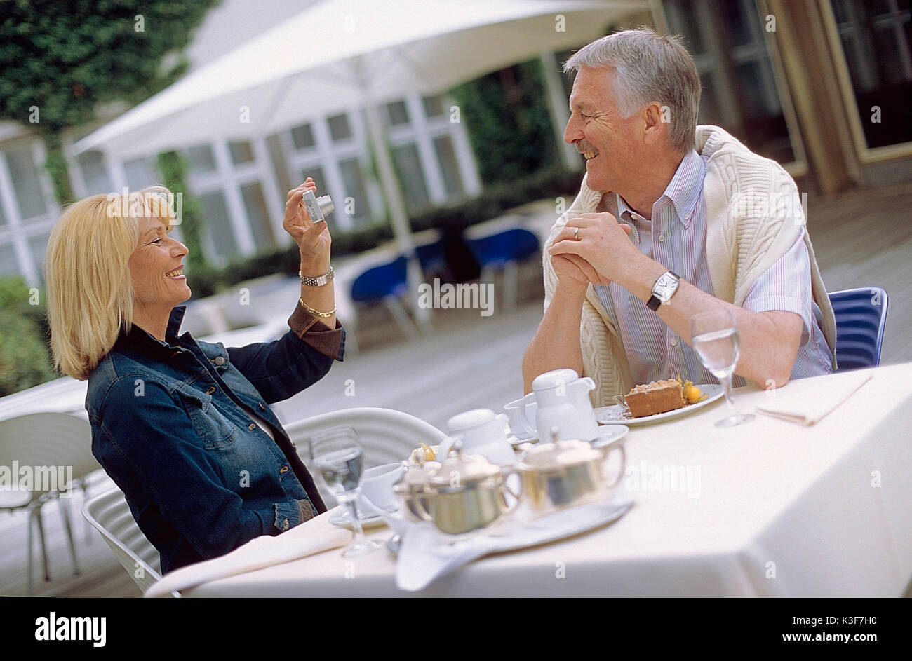 La donna prende una foto di un uomo presso il cafe Foto Stock