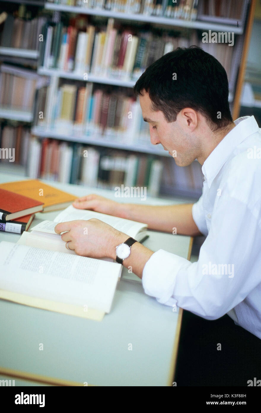 Uomo legge libro in una libreria Foto Stock